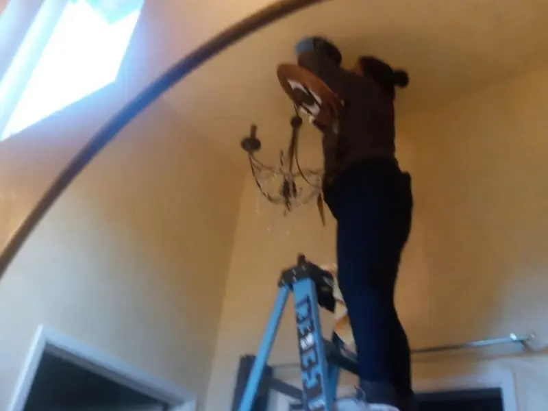Electrician installing a chandelier in a Thornton residence